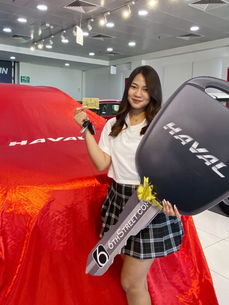 A women winning Haval car, holding a card and a big car key