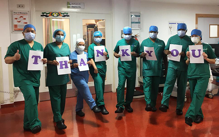 A medical team wearing Crocs shoes and holding cards to form thank you