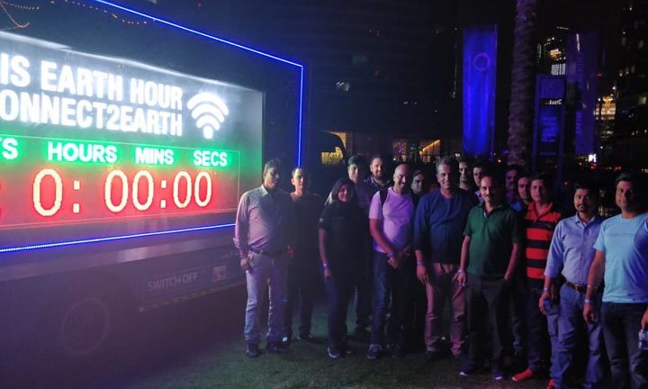 A group of people standing beside a truck of earth hour