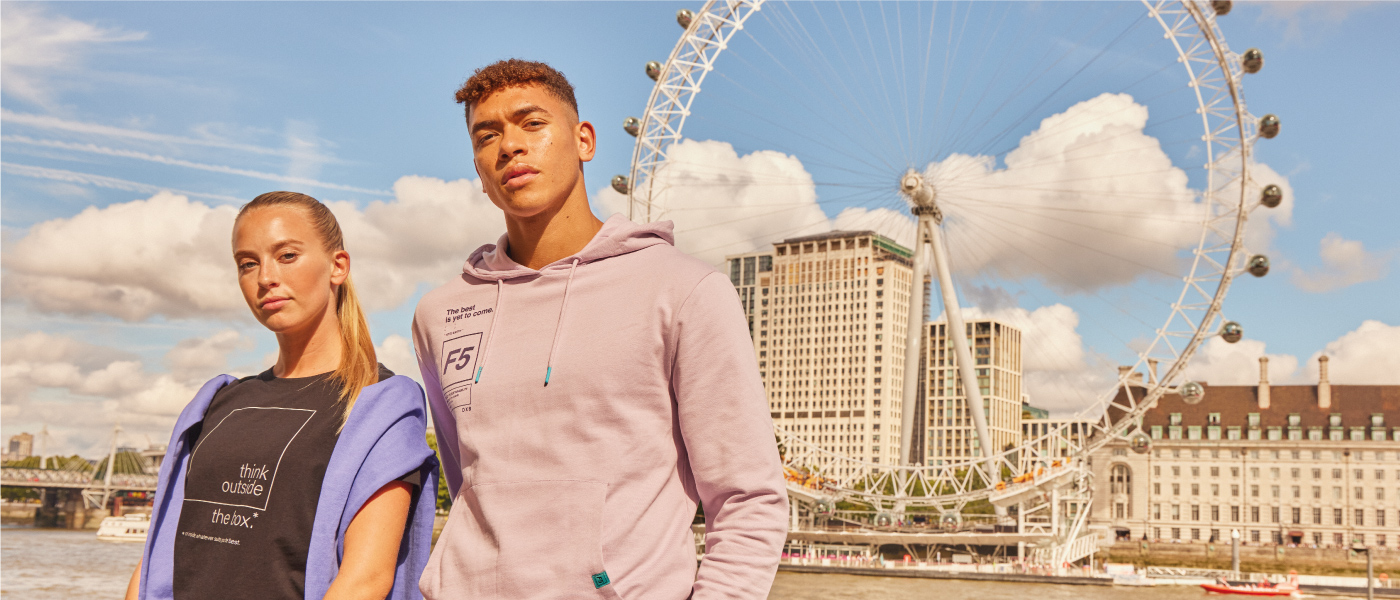 A young man and a young woman wearing F5 brand clothes and standing in front of the Ferris wheel