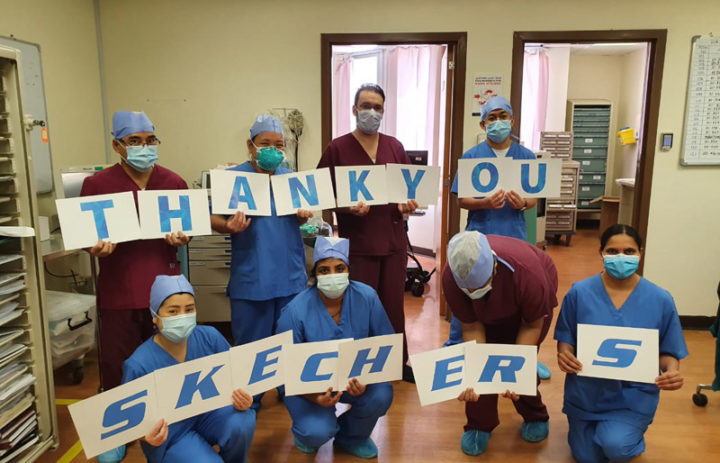 A medical team holding cards to form thank you Skechers