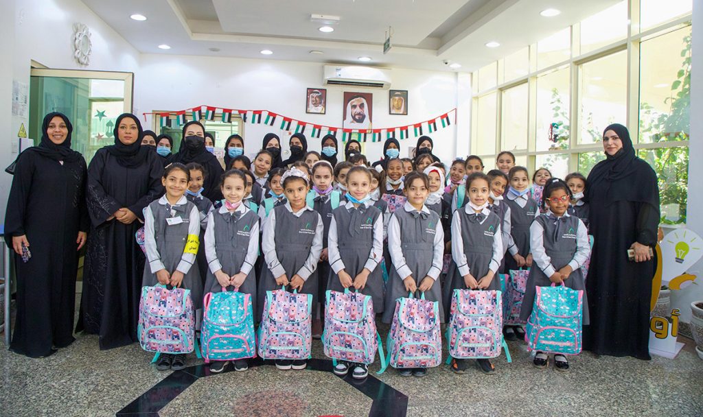 A group of students carring their bags and standing with their teachers