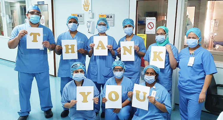 A medical team holding letter cards to form thank you