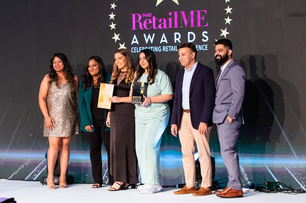 2 women holding awards surrounding by 2 women and 2 men