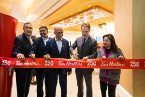 4 men and a woman cutting the tape of Tim Hortons