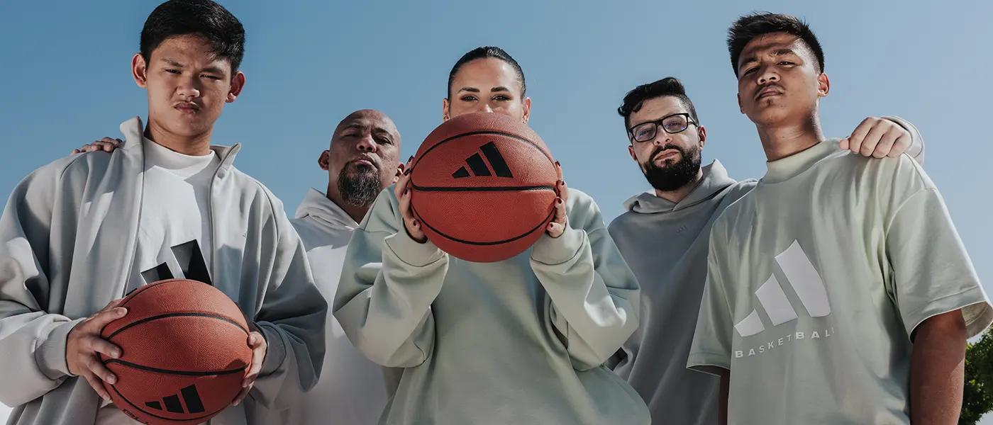 Four men and a woman wearing Adidas brand and holding basketballs