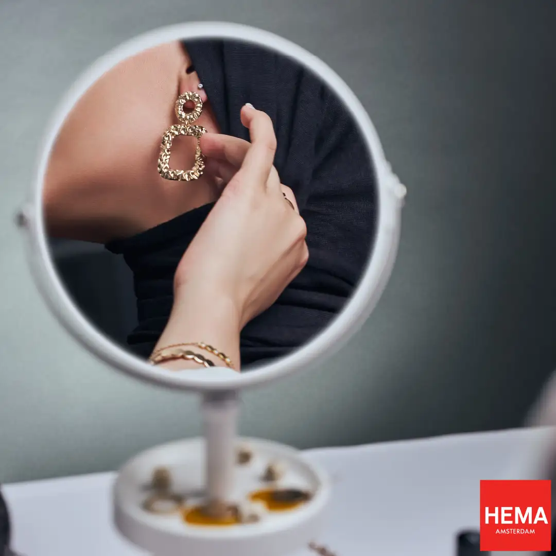 A woman looking at her HEMA earrings in the mirror