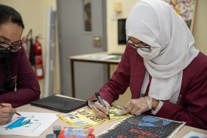 2 women wearing masks drawing on the table