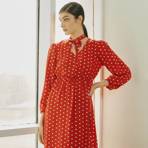 A woman wearing a red polka dot dress from His & Hers